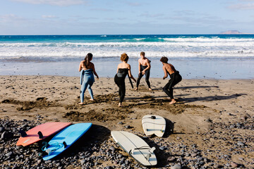 Diverse friends taking an outdoor surf theory class on a sunny beach