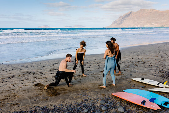 Surfing enthusiastic friends take a lesson with a professional surfer