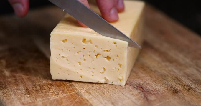 a piece of cheese with holes in place of slicing for cooking, pieces of sliced cheese on a cutting board