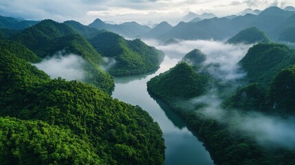 Obraz premium Lush green mountains and serene river with misty clouds in tranquil landscape