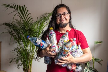 Man recycling plastic at home. Plastic bottles filled with packaging. Making 'Bottles of love'....