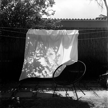 Picture of white sheet hanging in a garden with a round chair