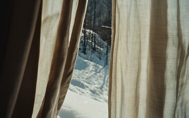 Sunlight streams through sheer beige curtains, revealing a snowy winter landscape beyond. A path is visible through the snow-covered trees