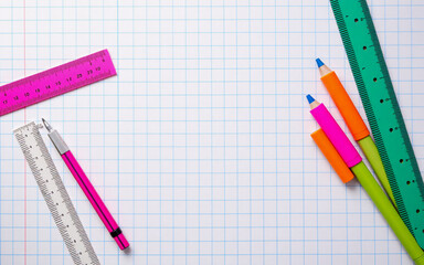 Bright school supplies including rulers and pencils are arranged on graph paper.  The tools are colorful and ready for learning or creative projects.