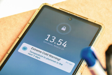 Extreme Cold Warning weather alerts on mobile screen. Real-time mobile notifications push...