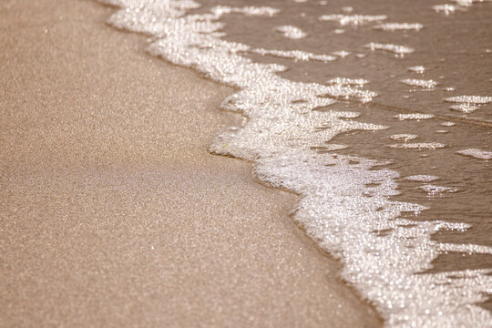 Close-up of the foamy edge of water on a beach.