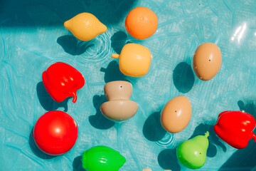 Colorful plastic toy fruits and vegetables floating in water