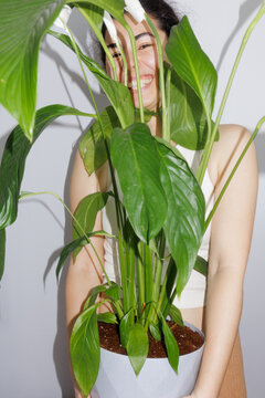 Portrait of a young woman with a large potted houseplant.