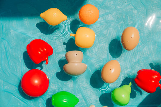 Colorful plastic toy fruits and vegetables floating in water