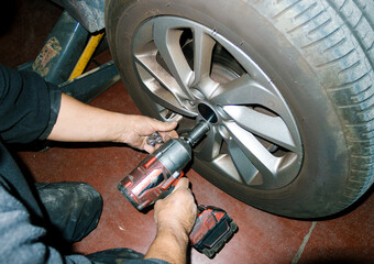 Mechanic using impact wrench removing wheel bolts in auto repair shop