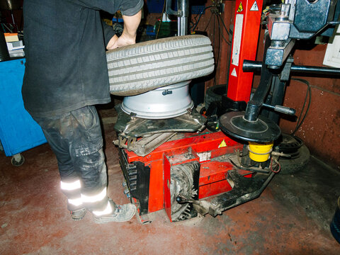 Mechanic changing tire using professional equipment in garage