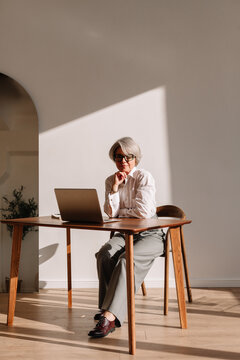 Fototapeta Elderly woman working thoughtfully at a desk in a sunlit room