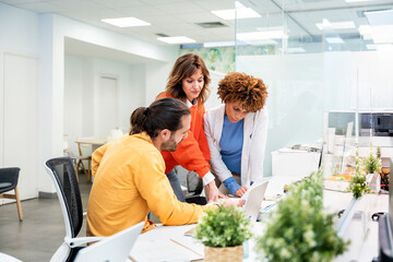 Office workers collaborating on project using laptop