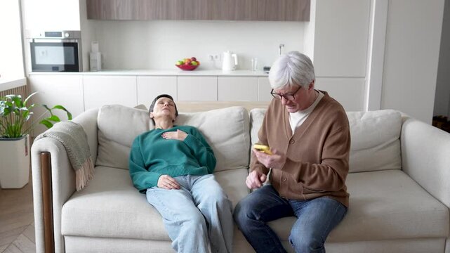 Frightened frantic hurry husband dialing for ambulance as wife suffers heart attack, in faint nearly on couch. Panic, medical emergency, cardiac arrest, immediate help, overwhelming fear, urgency call