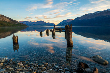 Old jetty surrounded by mountains reflecting in the water