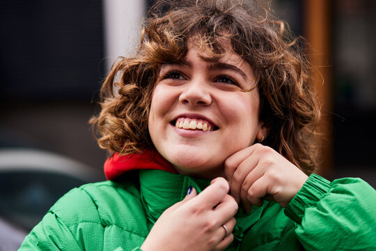 Smiling woman buttoning her jacket