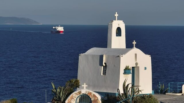 A ferry boat arrives at Rafina Port with a white chapel in the foreground