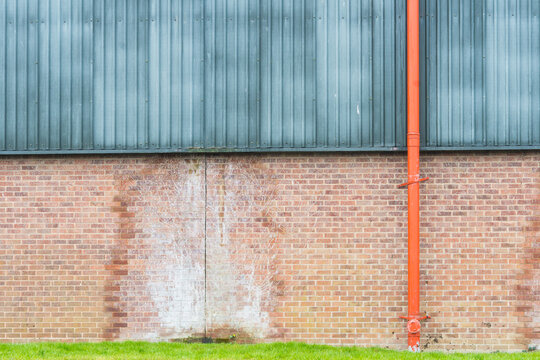 Red drainpipe on an industrial building wall.