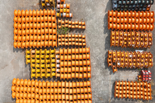 Aerial view of stacked empty orange and yellow cable spools.