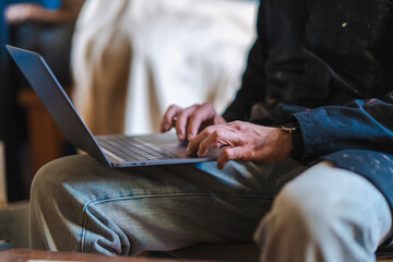 Detail of a male artist sits his studio with a laptop.