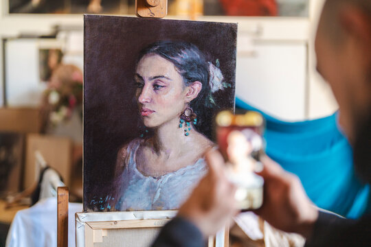 A male artist captures a photo of his painting.