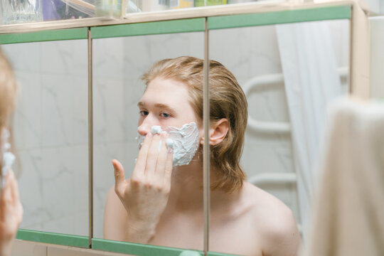 Person Applying Shaving Cream in Front of Mirror