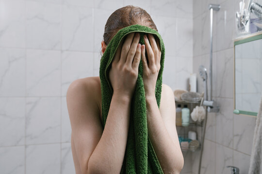 Young man drying face with towel in bathroom