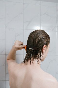 Young man combing wet hair in bathroom
