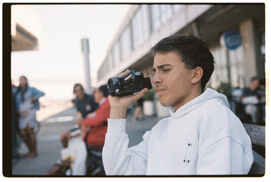 Boy in a white hoodie using a Camcorder