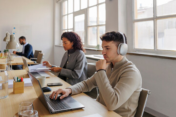 Focused formal employees working on laptops in modern office