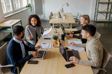 Diverse formal business team collaborating on project in m office
