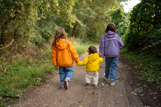 Siblings wander a forest with colourful jacket