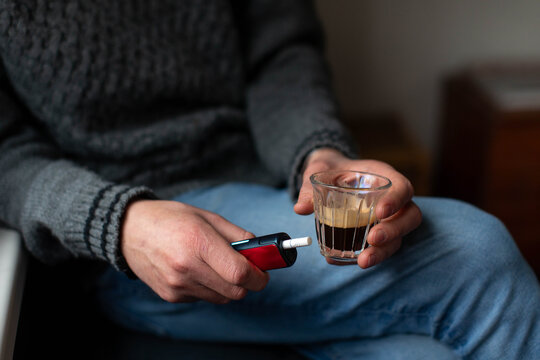Man sits with electronic cigarette and coffee