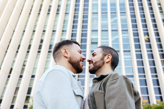 Romantic moment between a gay couple beneath city architecture