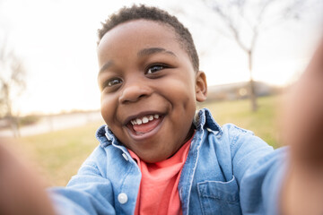 Happy child taking a selfie in a park smiling and having fun