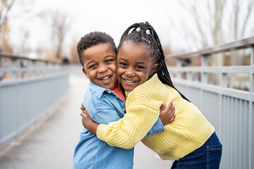 Two happy children hugging on a bridge in a park