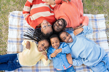 Happy family lying on blanket in park enjoying sunny day