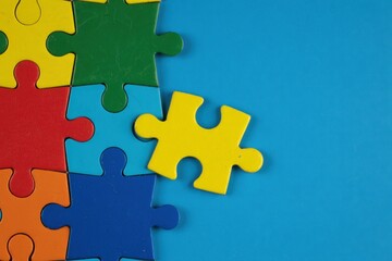 Obraz premium Colorful jigsaw puzzle pieces on a vibrant blue background, with a single yellow piece fitting into the pattern perfectly.