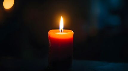 Single orange candle burning in dark space
