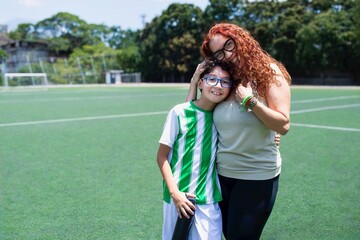 Soccer mom hugging her son after a soccer match on field