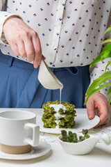 Woman pouring sauce over washli with spinach.