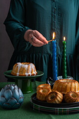 A woman in a green dress lights candles for the Easter holiday.