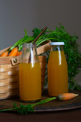 Healthy eating. Two bottles of fresh carrot juice on the table against the background of a wicker basket with carrots.
