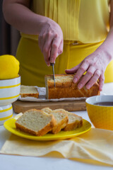 Woman in yellow clothes cutting lemon cake.