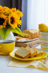 On the table in a yellow plate are cut pieces of lemon cake.
