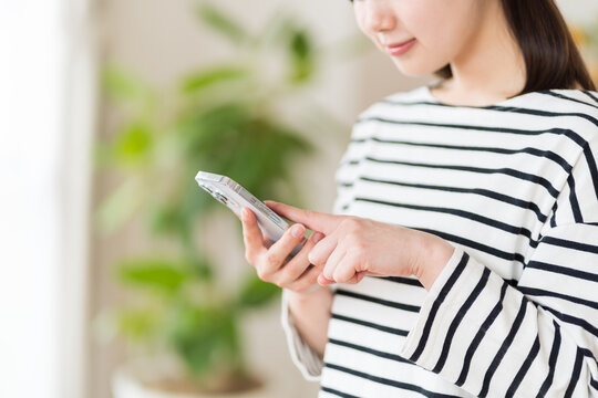 スマートフォンを操作する若い女性（パーツモデル）