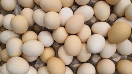 Close up of randomly stacked chicken eggs sold at the market as a background.