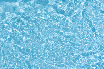 Fototapeta premium Blue water with ripples on the surface. Defocus blurred transparent blue colored clear calm water surface texture with splashes and bubbles. Water waves with shining pattern texture background.