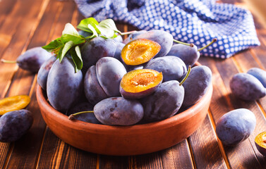 Fresh plums on plate over dark wooden background