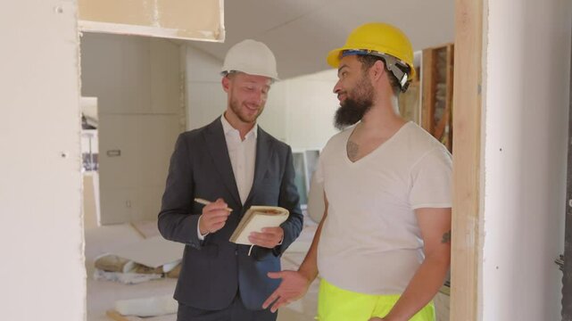 At a busy renovation site, a skilled construction professional discusses the project indepth with a diligent worker, effectively collaborating to ensure the success of their efforts